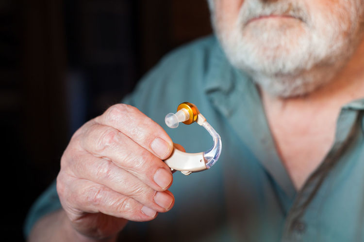 Midsection close-up of man holding hearing aid