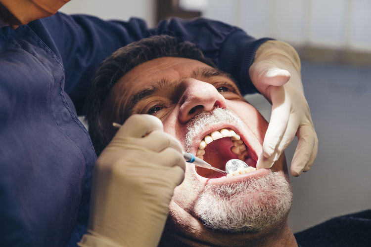 Cropped image of dentist using angled mirror while examining patient's teeth