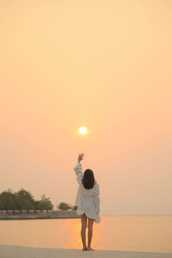 Rear view of woman standing on street during sunset