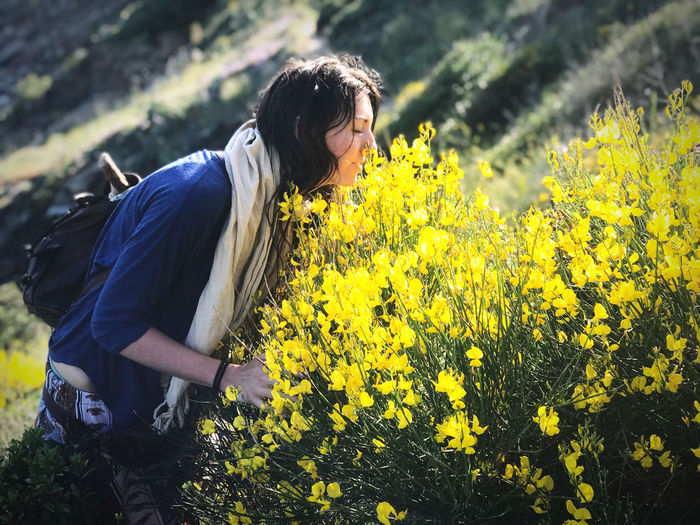 A woman smelling yellow flowers near the sea