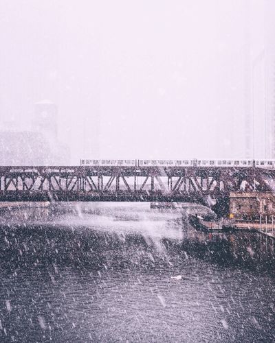 Bridge over river against sky during winter