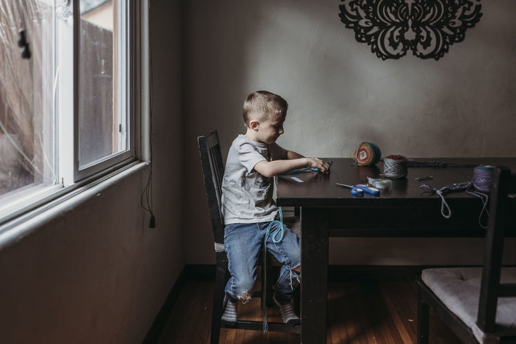 Side view of boy sitting on table at home