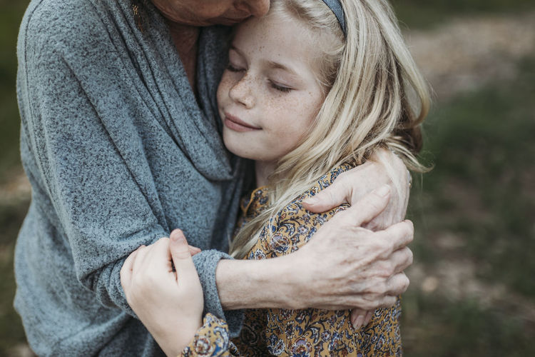 Detail image of young girl being hugged by senior grandmother