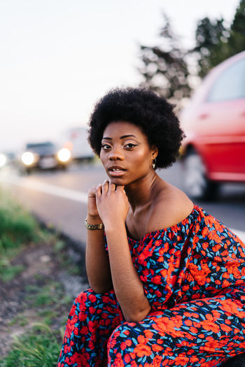 Portrait of young woman sitting by road