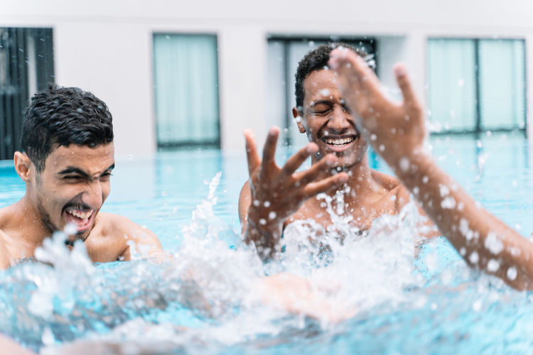 Man smiling as he plays in a circle with a group of friends in a pool