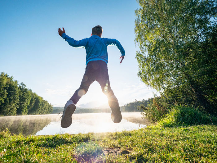 Full length of man jumping on grass against sky