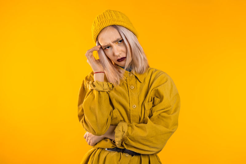 Portrait of woman wearing hat against yellow background