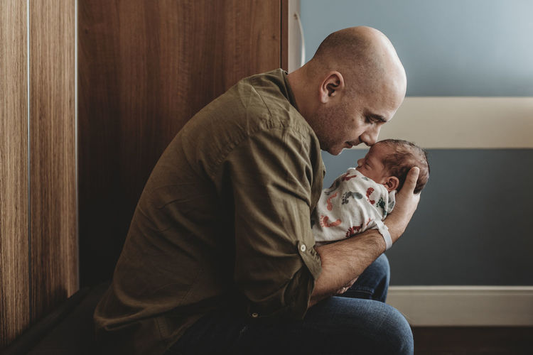 Side view of happy father embracing newborn son in hospital