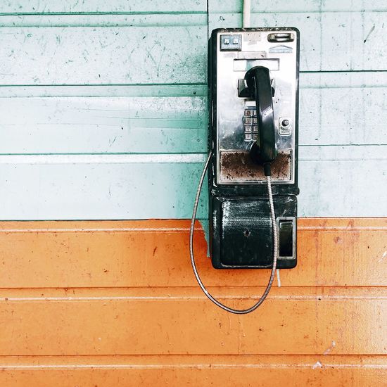 Close-up of old pay phone mounted on wall