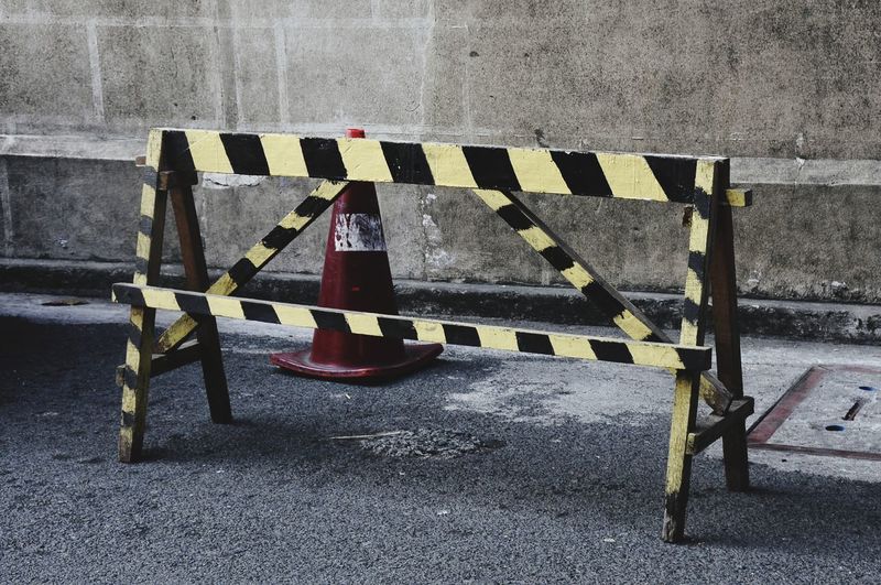 High angle view of barricade with traffic cone on road against wall