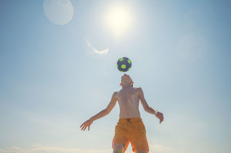 Low angle view of man playing with ball against sky