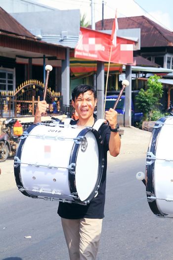 Portrait of smiling man with drum on street in city