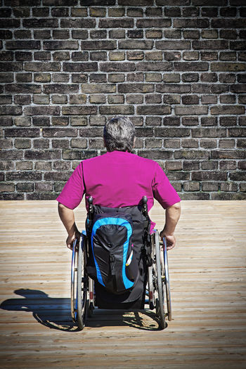 Rear view of woman sitting on brick wall