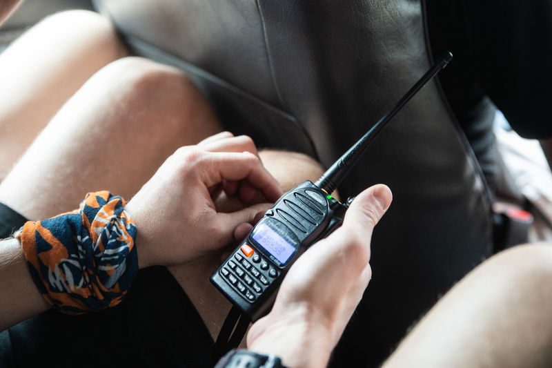 Midsection of man holding walkie-talkie in car