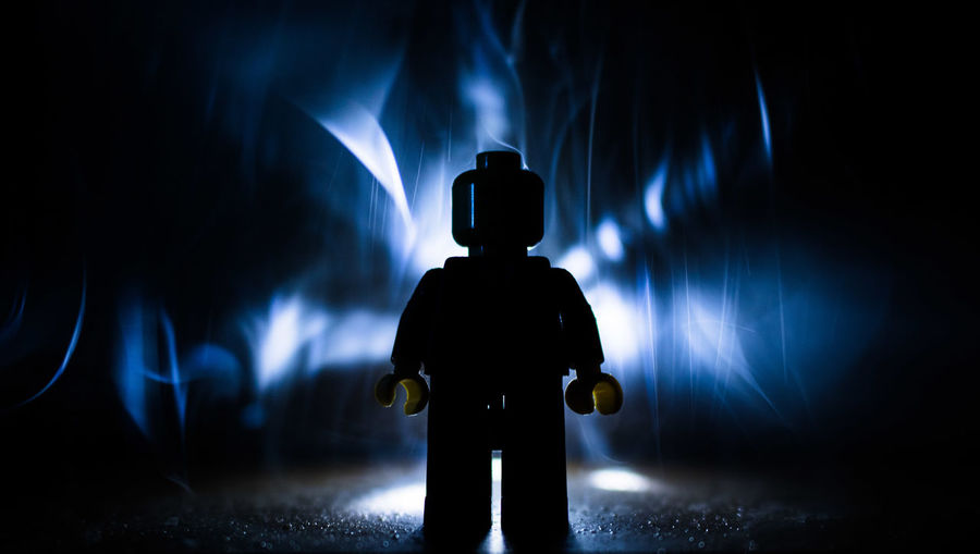 Rear view of silhouette person standing against illuminated light