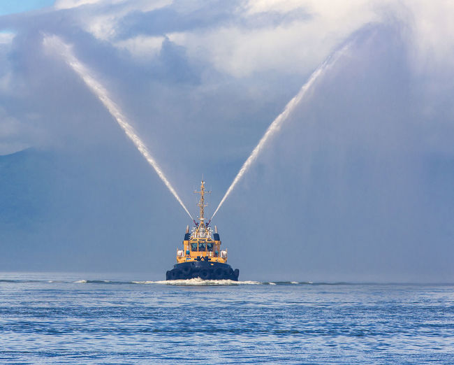 Fire hose boat spraying water on kamchatka on paciic ocean