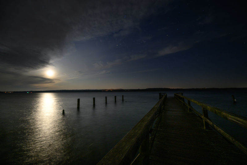 Wooden pier over sea against sky at sunset