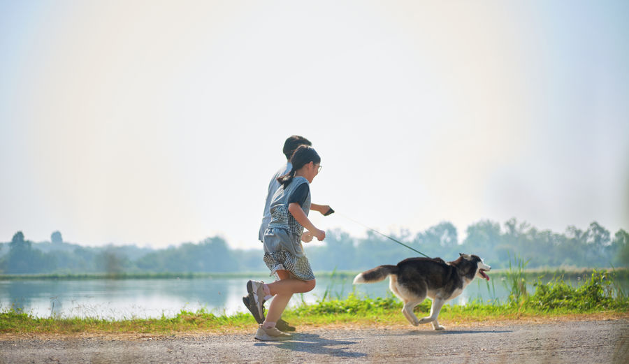 Full length of children playing by lake against sky