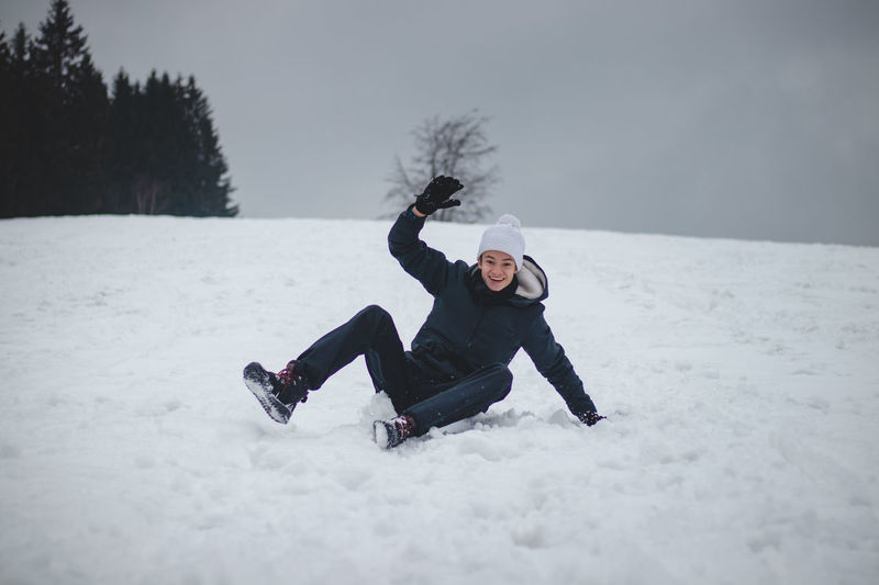 Teenager falls from a plastic snowboard and falls hard on the snow and sprawls. inventing nonsense