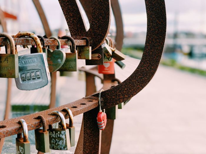 Love locks hanging outdoors by the harbor on a circular rusty globe 