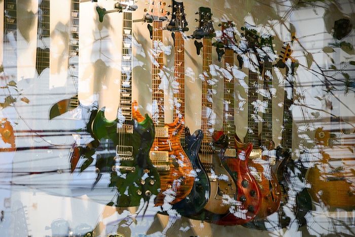 Guitars on display in store with reflection on glass window