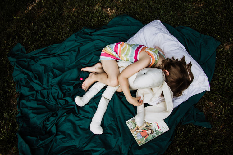 High angle view of girl with stuffed toy lying on blanket