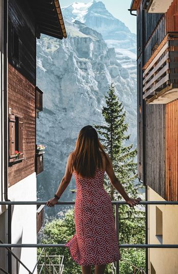 Rear view of woman standing by building against mountain