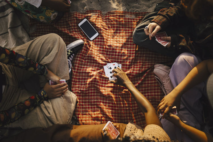 Multiracial friends playing cards at beach