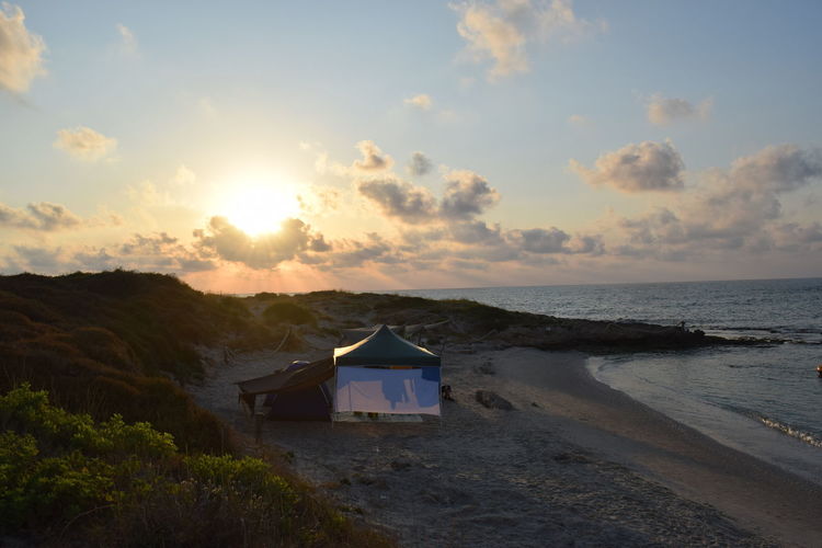 Scenic view tent on beach at sunset