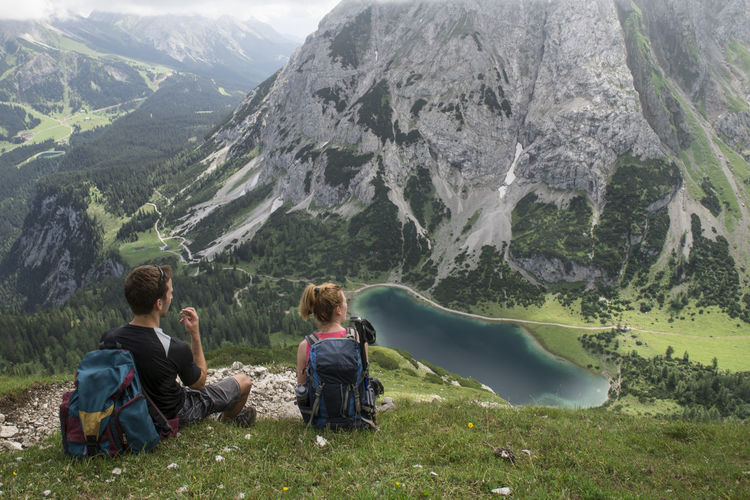 Rear view of couple sitting on mountain at ehrwald