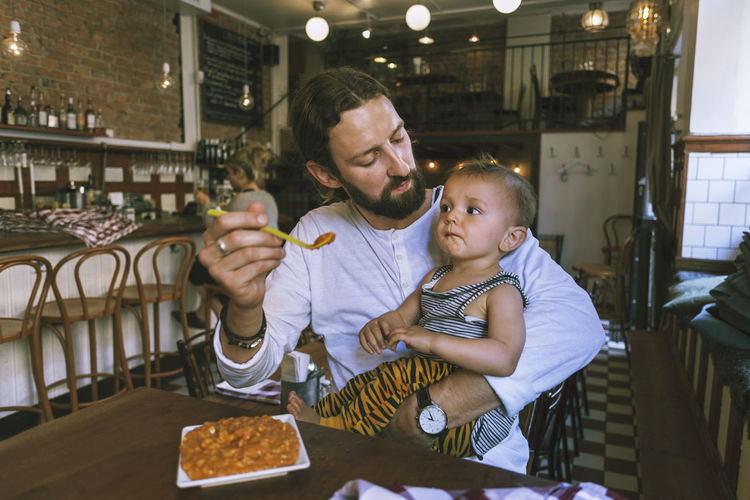 Mid adult man feeding baby boy at restaurant table