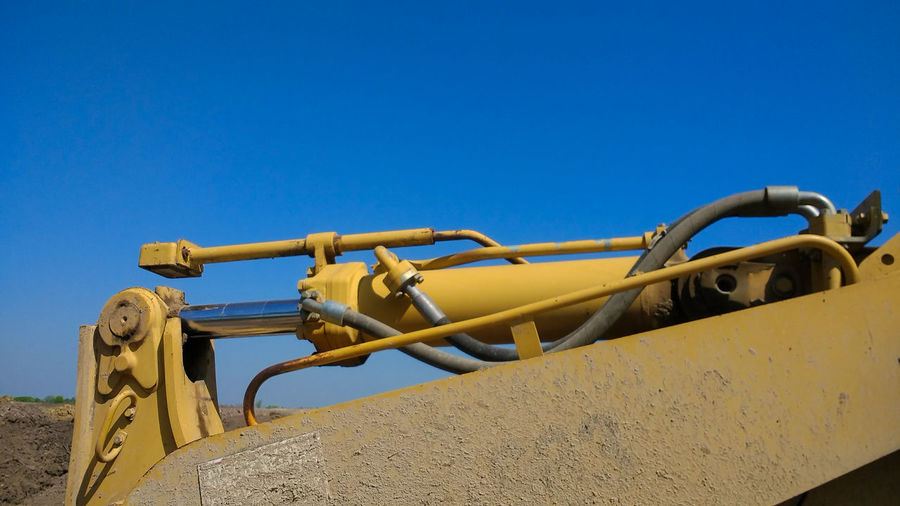 Low angle view of machinery against clear blue sky