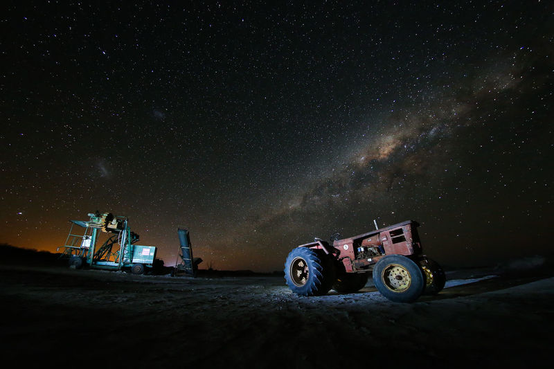 Construction machineries on field against star field
