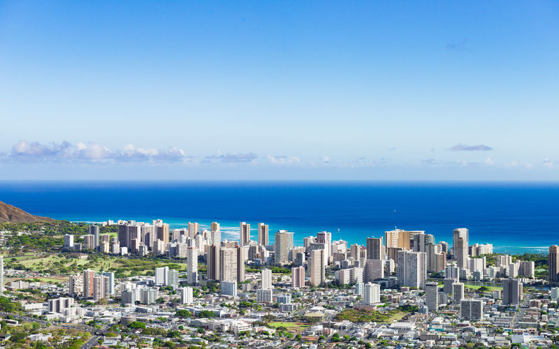 Cityscape by sea against blue sky