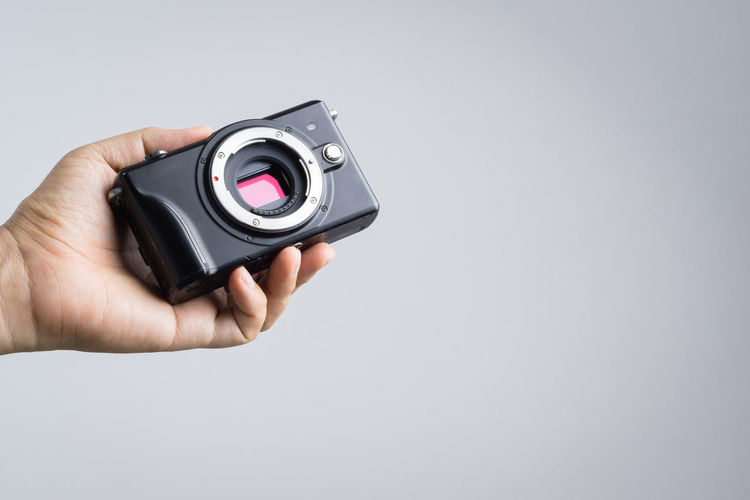 Close-up of hand holding camera against white background