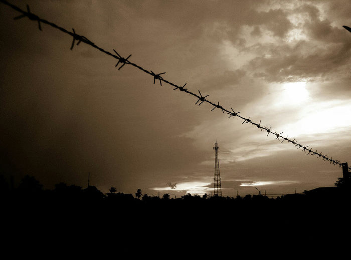 Silhouette of barbed wire against sky during sunset