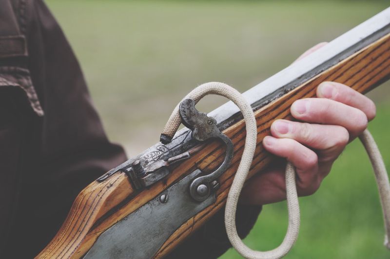 Close-up midsection of man holding old rifle