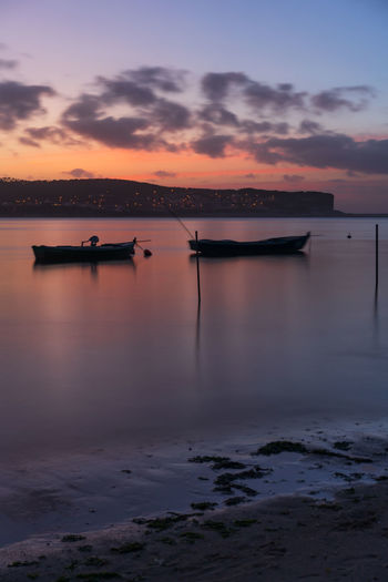 Fishing boats on a river sea at sunset in foz do arelho, portugal