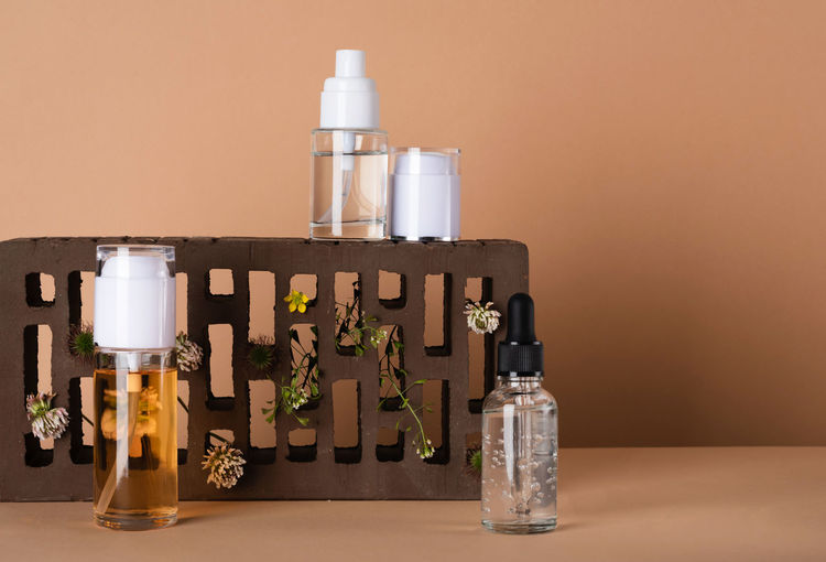 Liquid beauty products with wild plants on a brick podium. cosmetic bottle with care product. 
