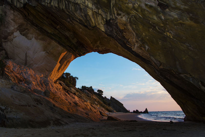 Scenic view of sea seen through cave during sunset