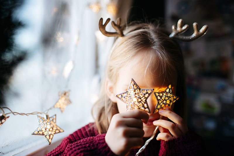 Close-up of girl playing with christmas lights 
