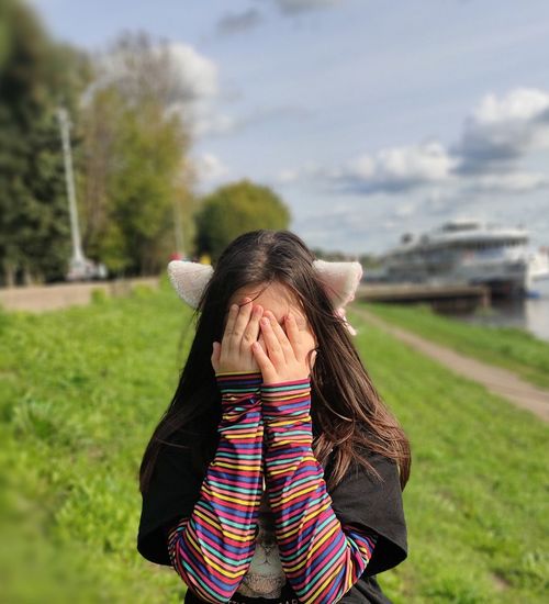 Cute girl covering face standing outdoors
