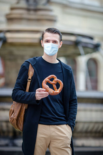 Portrait of man wearing mask holding food outdoors