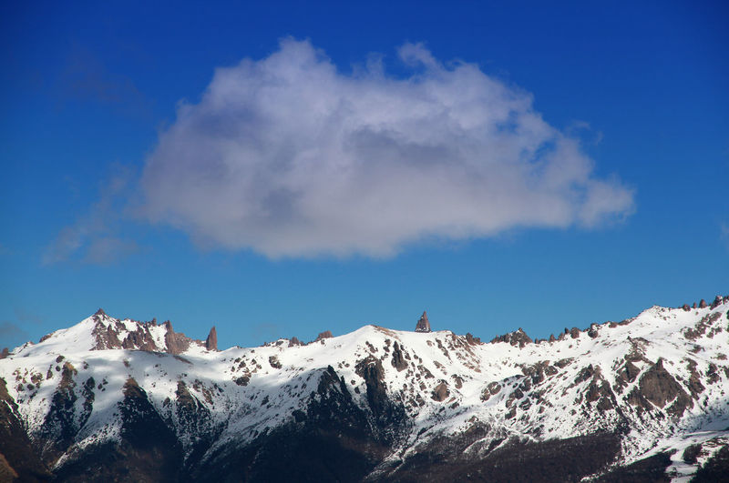 Scenic view of snowcapped mountains against blue sky
