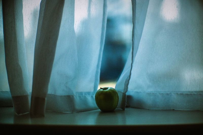 Close-up of granny smith apple on window sill