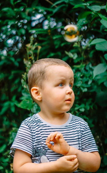Portrait of cute boy standing against plants