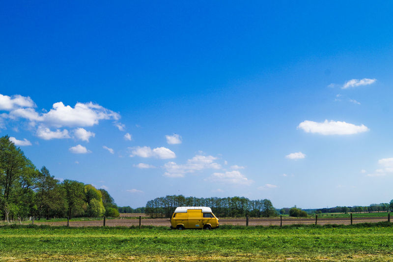 Yellow car on field against sky
