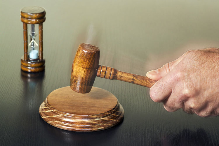 Cropped hand of lawyer holding gavel at table