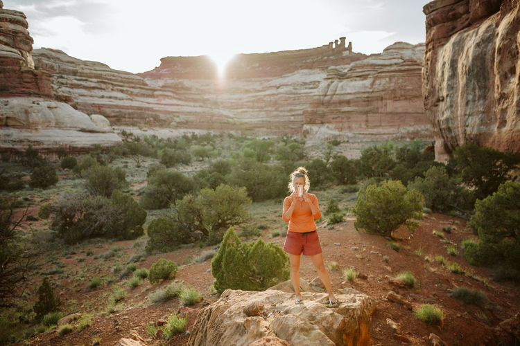 Female in workout clothes takes picture with cellphone in desert light