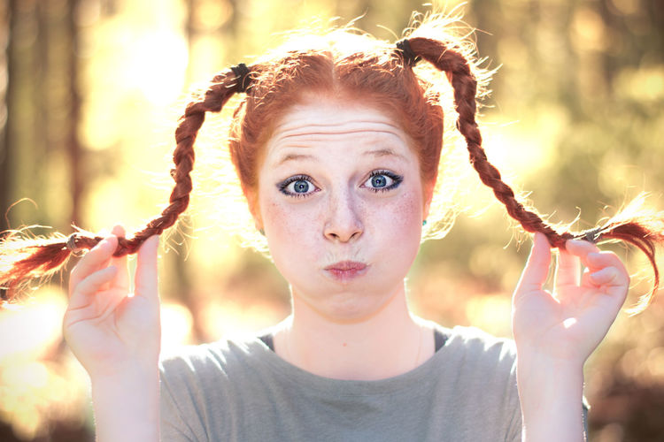 Portrait of woman with puffed cheeks holding pigtail braids